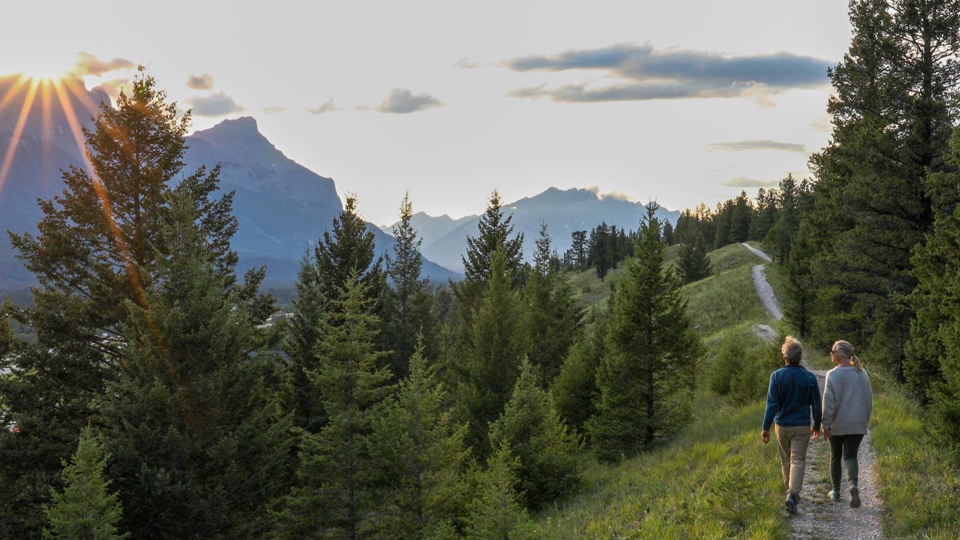 A couple walking a mountain trail at golden hour