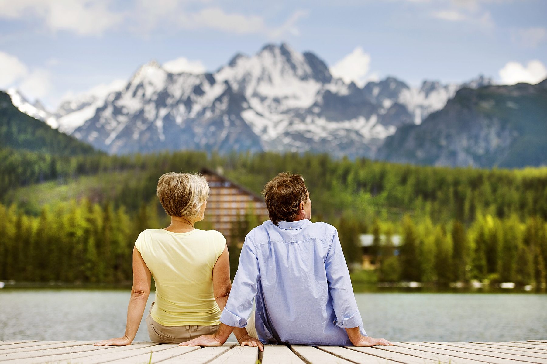 A retired couple walking hand in hand on a lake dock